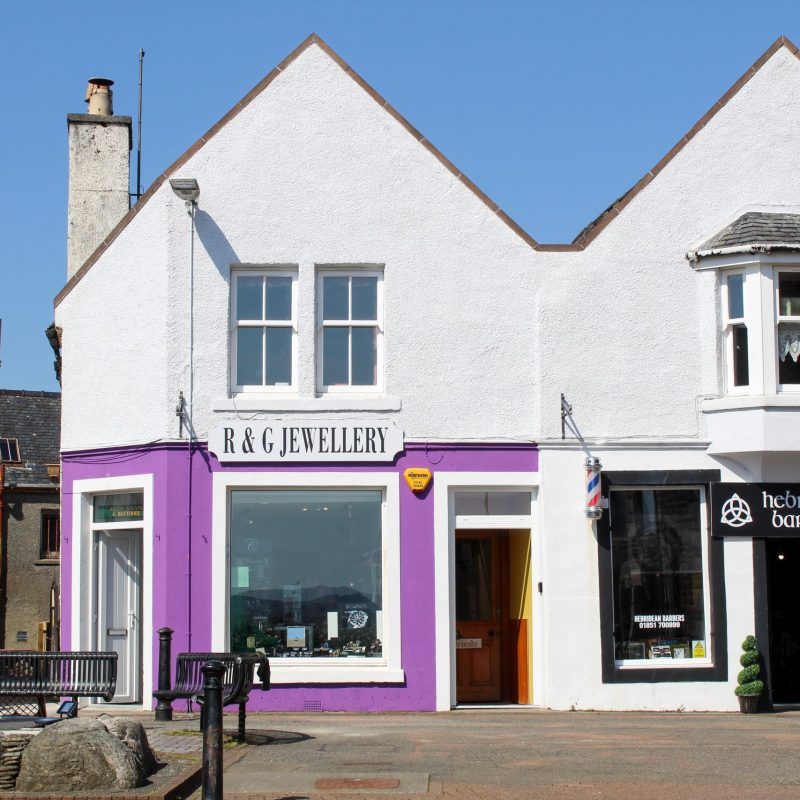 Image of R&G Jewellery shop front behind wooden 'Herring GIrl' statue in Stornoway